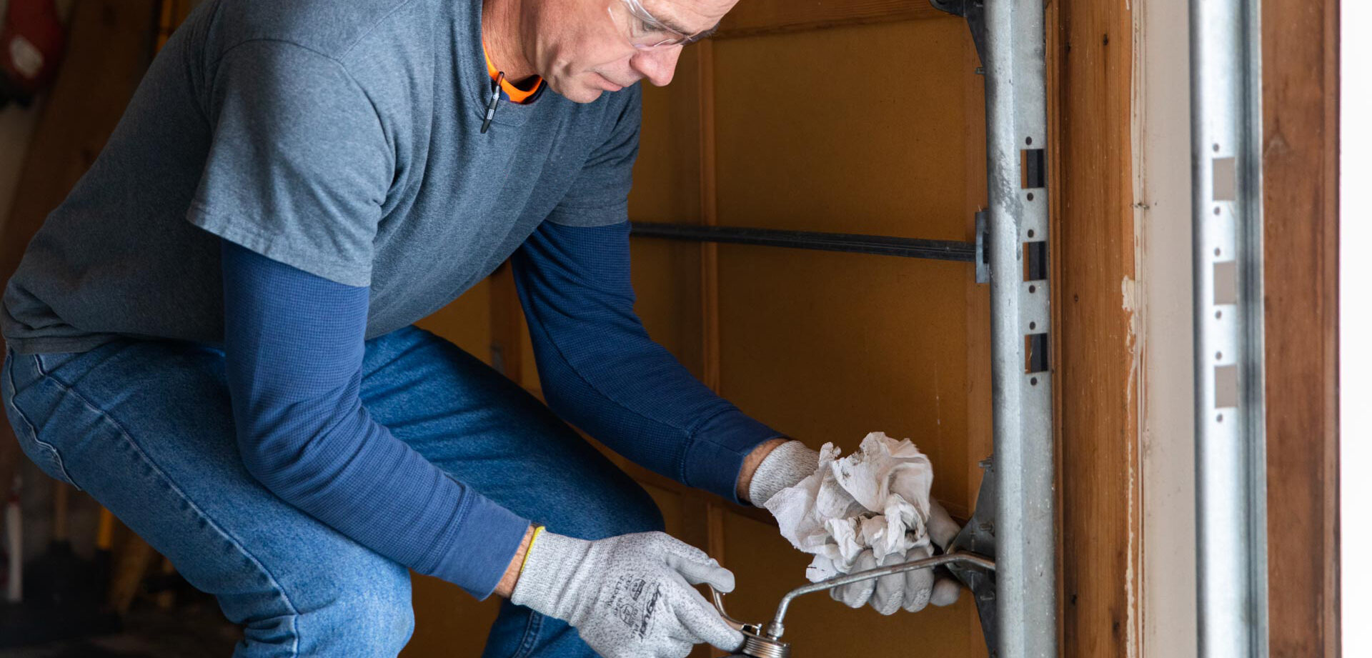 man greasing mechanical parts of garage door