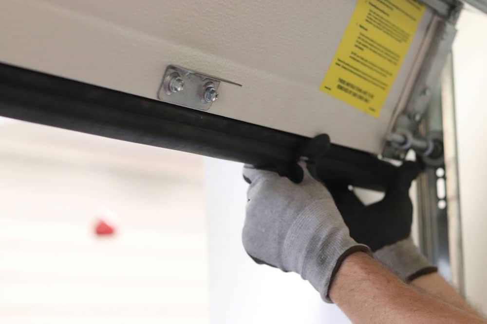 Person adjusting weather stripping on garage door